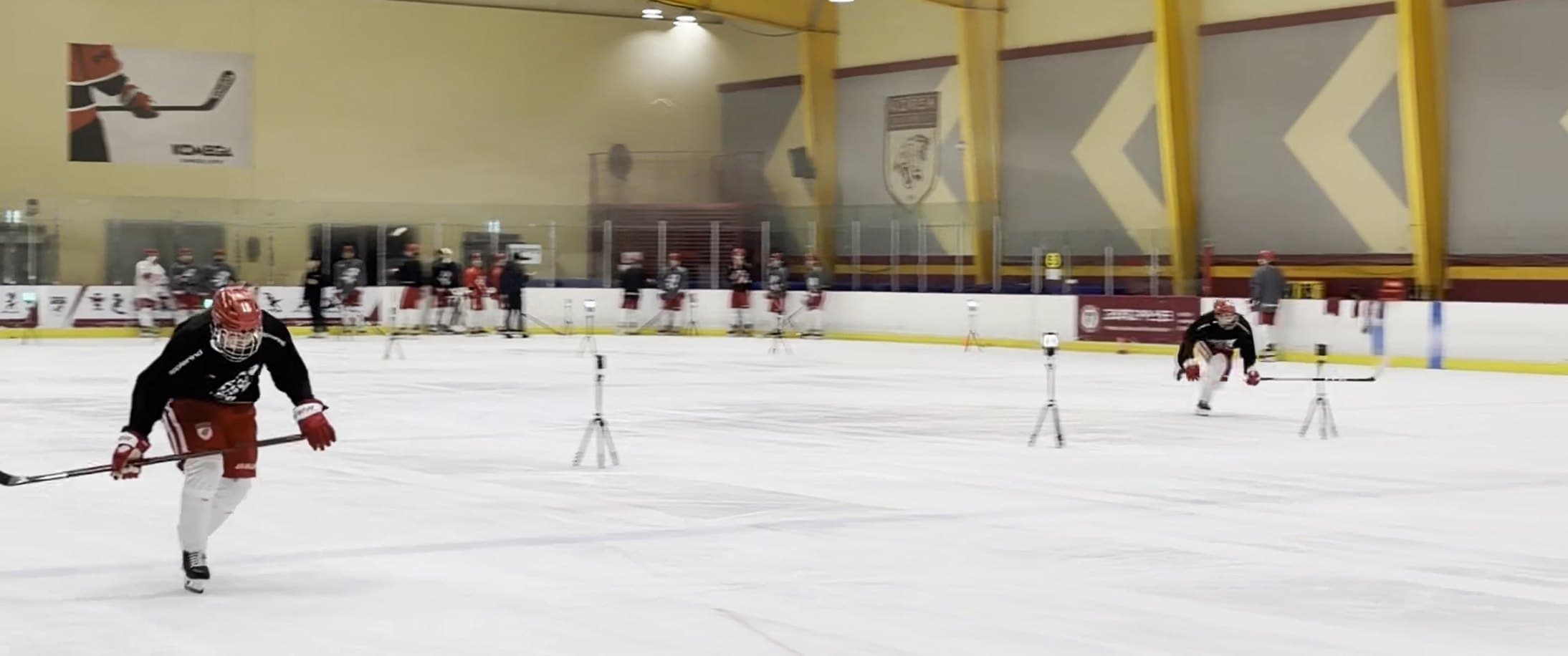 An ice hockey player passing between timing gates while the team waits